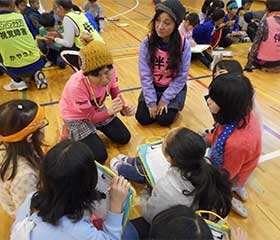 じゅんたん、フラを中心に、話を聞きいる小学生